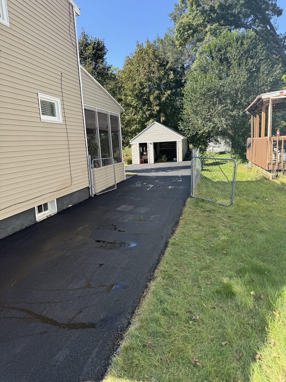 Fresh residential asphalt driveway toward garage